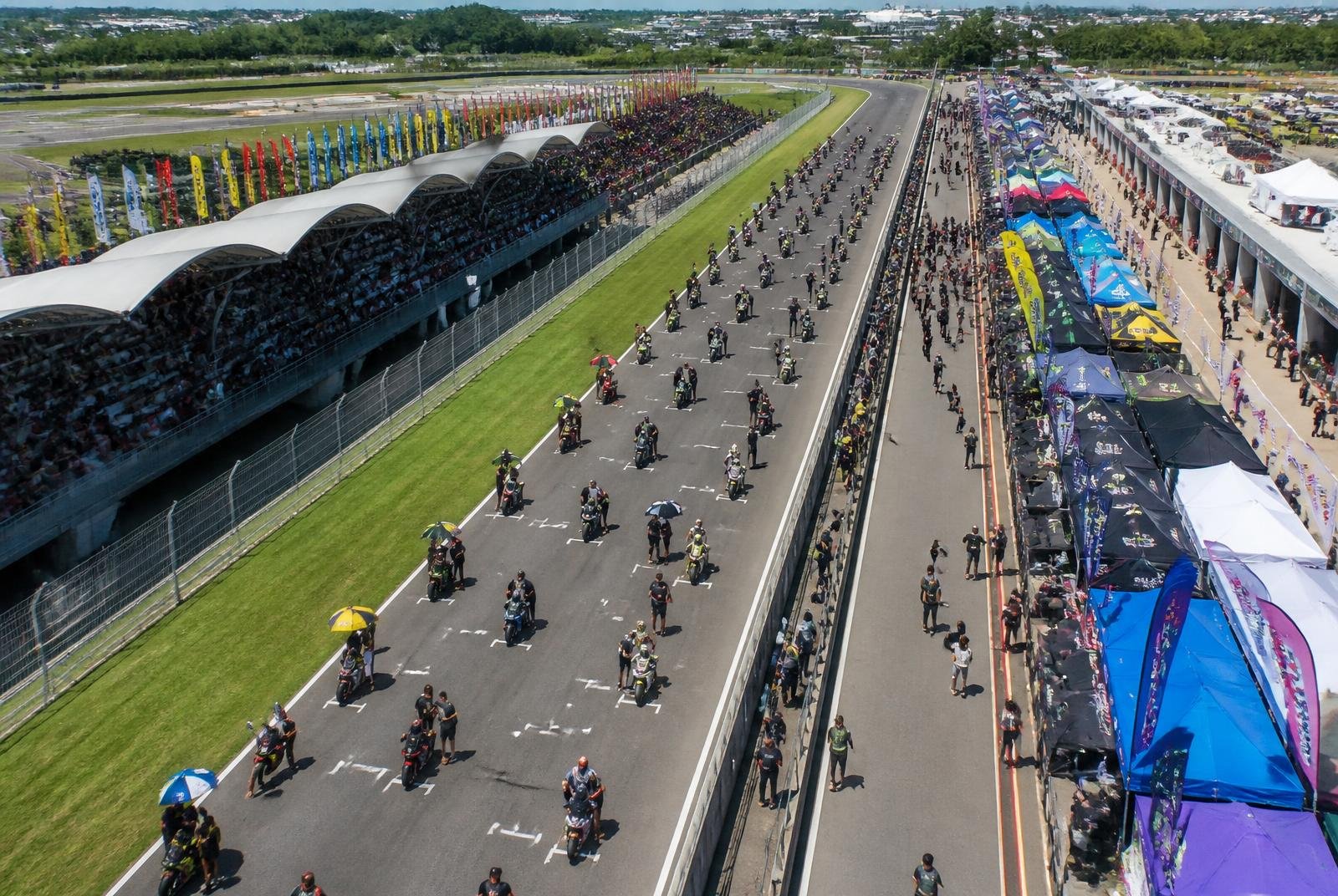 Visão aérea de evento de motovelocidade com equipes e público
